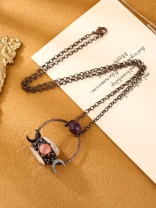 Detail of bronze crescent moon pendant with pink and purple quartz crystals on vintage cloth