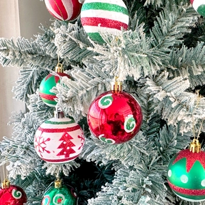 Detail of hand-painted Christmas ball ornaments with glitter on a snowy tree