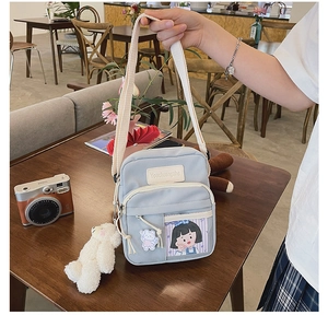 Gros plan d'un sac en toile gris-bleu avec charme ours en peluche et logo sur bureau