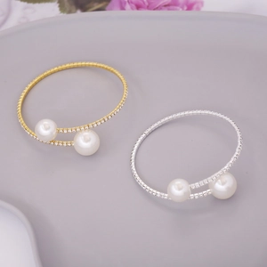 Elegant gold and silver pearl bracelets with sparkling rhinestones on a soft floral background
