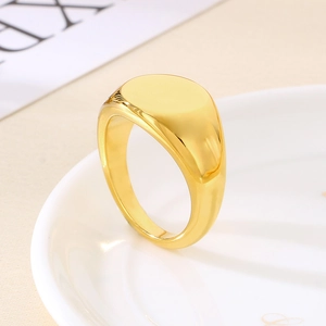 Close-up of polished 18K gold plated oval signet ring resting on a ceramic plate edge