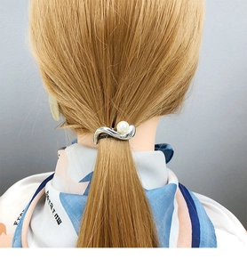 Detail of twisted silver hair clip with pearl on ponytail, minimalist elegant headwear