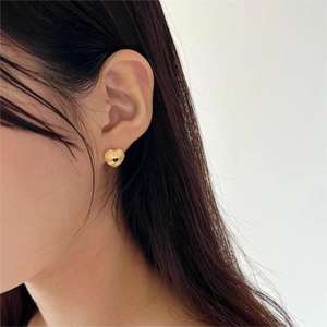 Close-up of golden heart-shaped stud earrings with textured finish on model