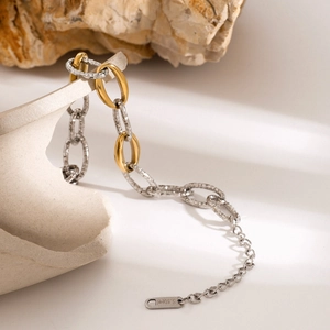 Detail of two-tone stainless steel chain bracelet with hammered links on stone pedestal