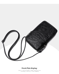Détail de la pochette téléphone en cuir noir grainé avec motif floral camélia gaufré