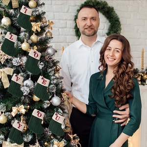 Close-up of green knitted Christmas stockings with red letter embroidery on a festive tree