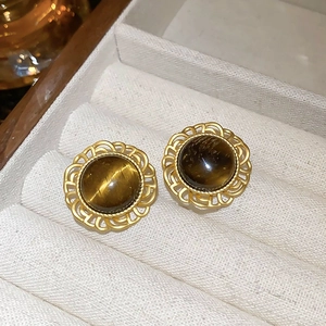 Macro shot of vintage gold-plated earrings with brown tiger eye stone in a jewelry box