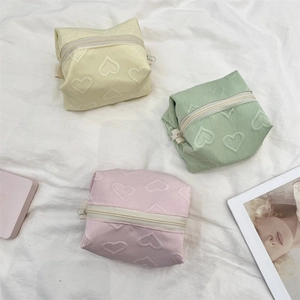 Détail de trousses à maquillage avec gaufrage cœur en jaune, vert et rose avec fermetures
