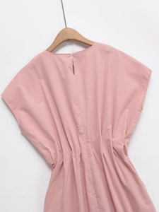 Détail d'une robe rose montrant le col rond et la fermeture à bouton goutte au dos