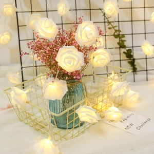 Detail of white rose LED string lights in warm glow inside a decorative wire basket