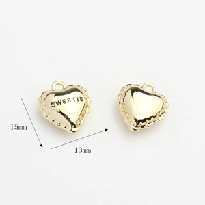 Macro shot of 15mm gold heart charm with Sweetie engraving and scalloped edges
