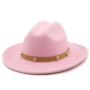Detail of pink wool fedora hat featuring a brown leather strap with gold metal studs