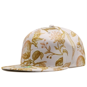 Detail of flat brim snapback featuring golden botanical leaf print on a white cap