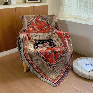 Couverture tissée bohème en coton avec motifs géométriques et franges sur fauteuil bois