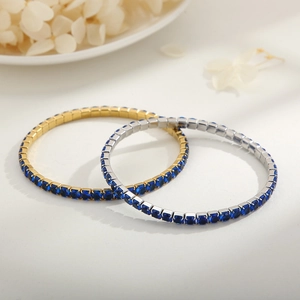 Detail of gold and silver tennis bracelets with blue stones on a white background