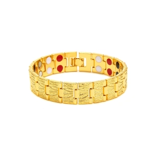 Macro detail of golden magnetic bracelet showing engraved patterns and inner therapy stones