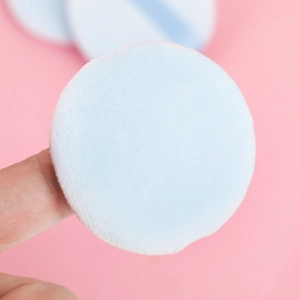 Macro shot of soft light blue velvet powder puff showing its plush texture and round shape