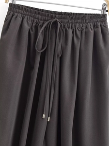 Detailed view of dark grey trousers showing elastic waistband and silver-tipped drawstrings