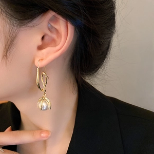 Detail of elegant gold linear drop earring with round white pearl on female model
