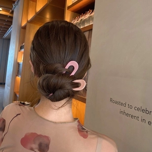 Pink matte U-shaped hair pin for buns shown on a model in a natural lifestyle setting