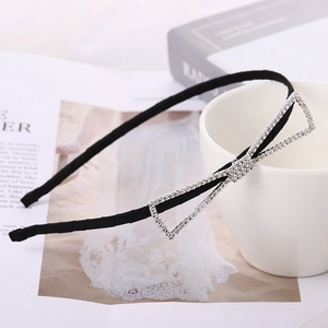 Elegant thin black headband with a large sparkling rhinestone bow on white ceramic