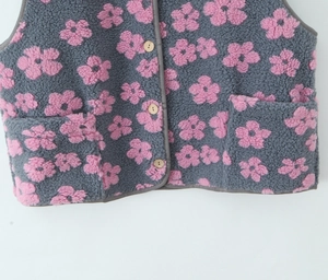 Close-up of grey fleece vest with pink flower patterns and wooden buttons detailing