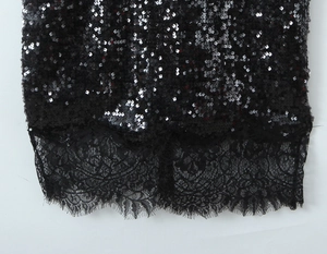 Gros plan sur le tissu à paillettes noires avec des détails d'ourlet en dentelle florale