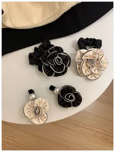 Detail view of camellia hair clips and scrunchies with pearls in black and white silk