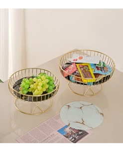 Detail of gold metal fruit basket with marble base holding grapes and snacks