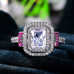 Macro shot of a rectangular halo emerald cut diamond ring with pink sapphire side accents
