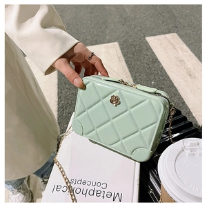 Macro shot of light green quilted jelly bag with golden chain and flower detail