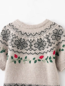 Close-up of Fair Isle geometric pattern and floral embroidery on beige knit sweater