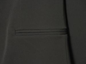 Détail de la couture de précision sur la poche d'une veste blazer tissée noire