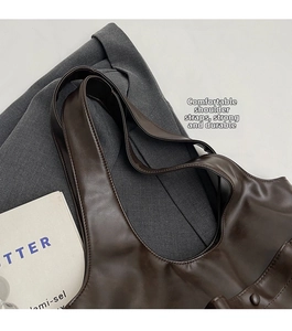 Detail of wide reinforced shoulder strap and neat stitching on brown leather handbag