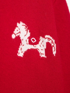 Close-up of red knit cardigan featuring white horse jacquard pattern and wool texture