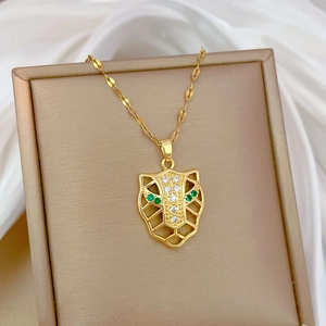Detail of gold leopard head pendant with green crystal eyes on a silk background