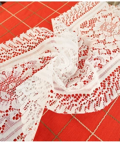 Close-up detail of white lace table runner showing intricate hollowed-out knitting pattern