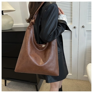 Brown vintage faux leather tote bag worn by a model in a minimalist modern interior