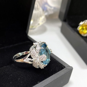 Macro shot of an oversized oval blue gemstone ring with butterfly accents on black velvet