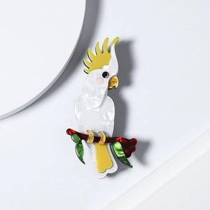 Detailed view of a handmade acrylic cockatoo parrot brooch perched on a branch