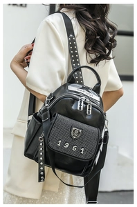 Close-up of black leather backpack strap with rivets and silver hardware detailing