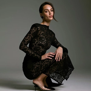 Close-up of elegant black lace dress featuring hollow floral patterns and sheer sleeves