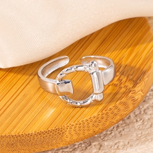 Macro shot of silver-tone stainless steel horsebit ring on a wooden display base