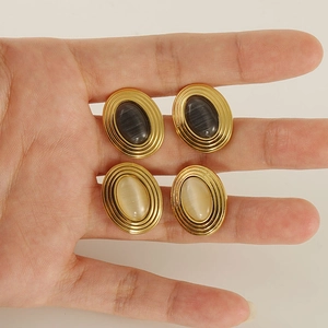 Macro detail of oval natural stone earrings with 18K gold plated textured metal frames