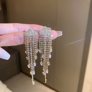 Detailed close-up of golden tassel earrings with sparkling rhinestones and crystal teardrops