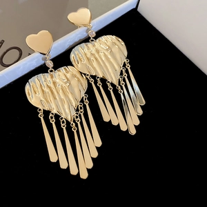 Macro shot of gold heart tassel earrings with metallic texture and rhinestone detail