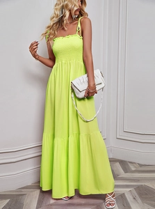 Detail of neon green maxi dress featuring a pleated bandeau top and flowy layered skirt