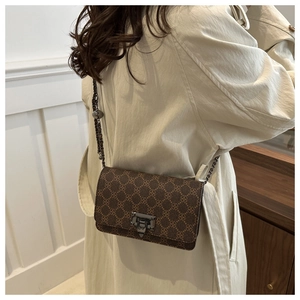 Detailed view of brown clover pattern crossbody bag with metal lock and chain strap