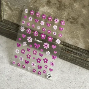 Macro shot of 3D embossed nail stickers featuring pink flowers and purple hearts