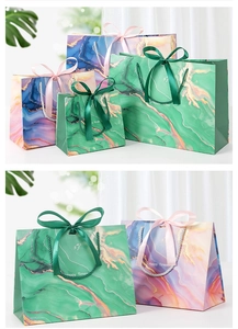 Detail of emerald green marble gift bags with gold accents and elegant ribbon handles